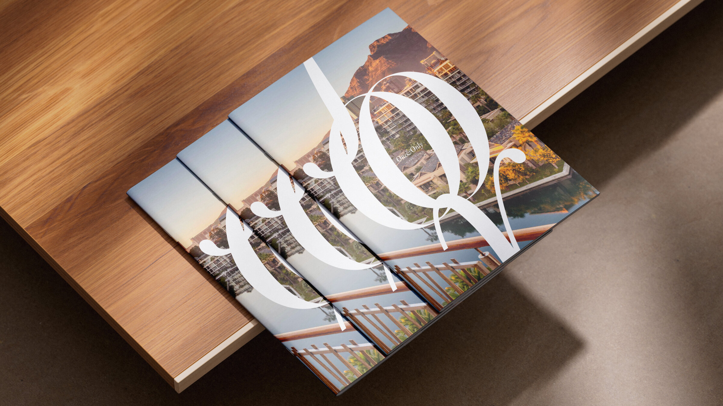 One&Only brochures fanned on a walnut table, the script monogram on the cover
