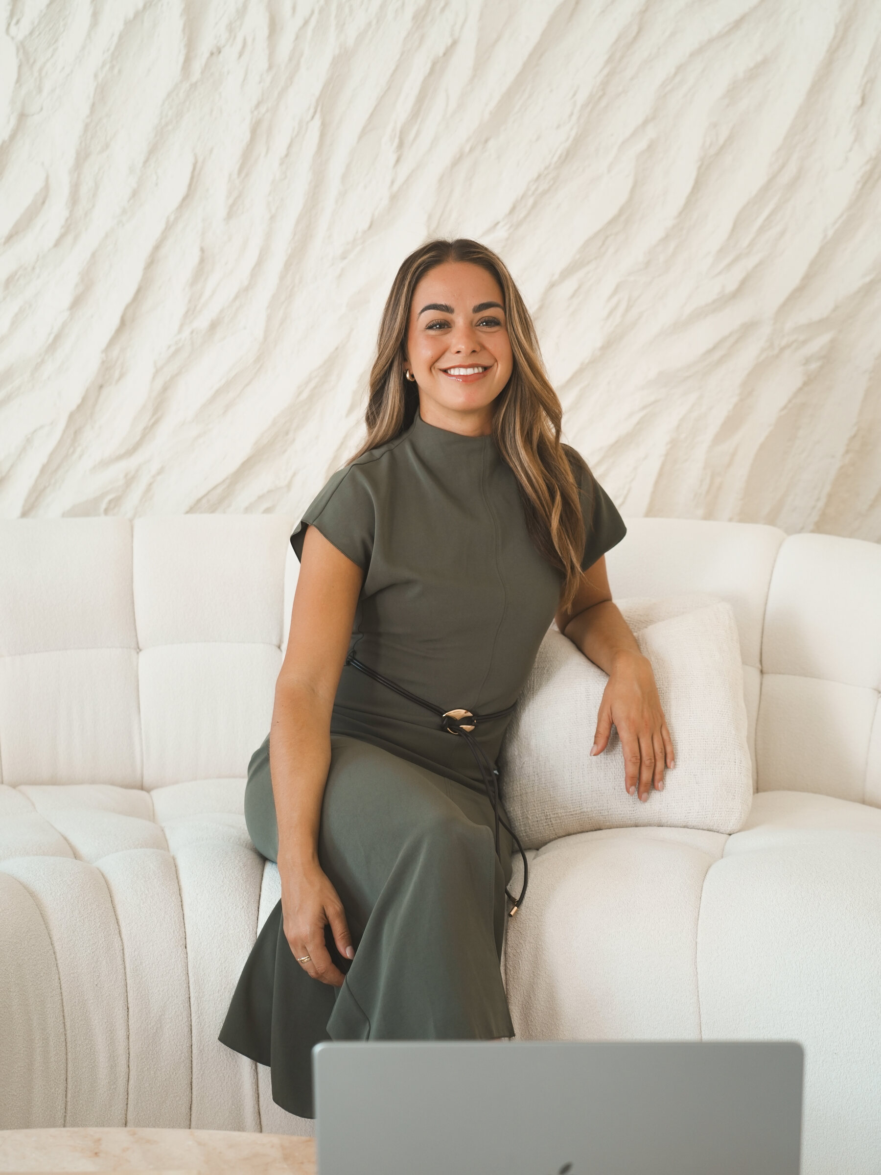 Chiara Colella on the studio sofa with her laptop, laughing