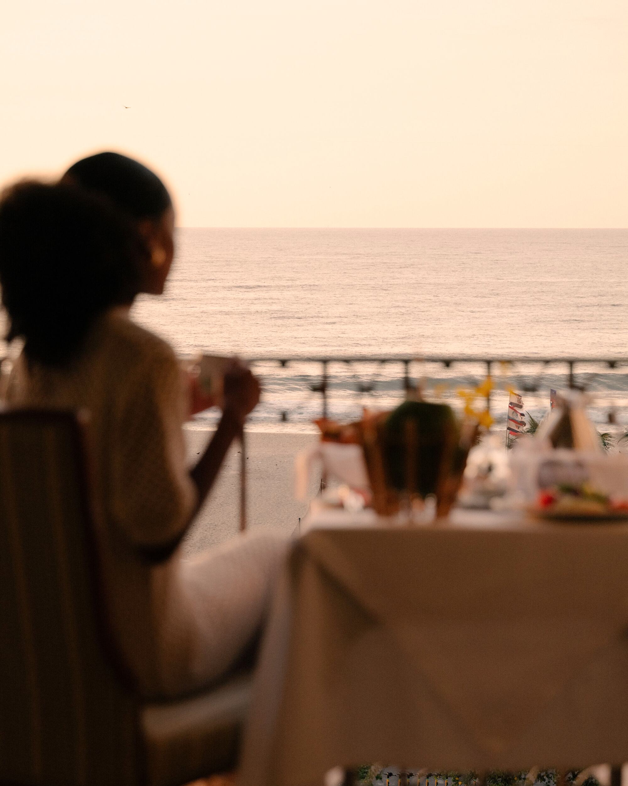 A guest with her morning coffee at a breakfast table, looking out over a hazy sea