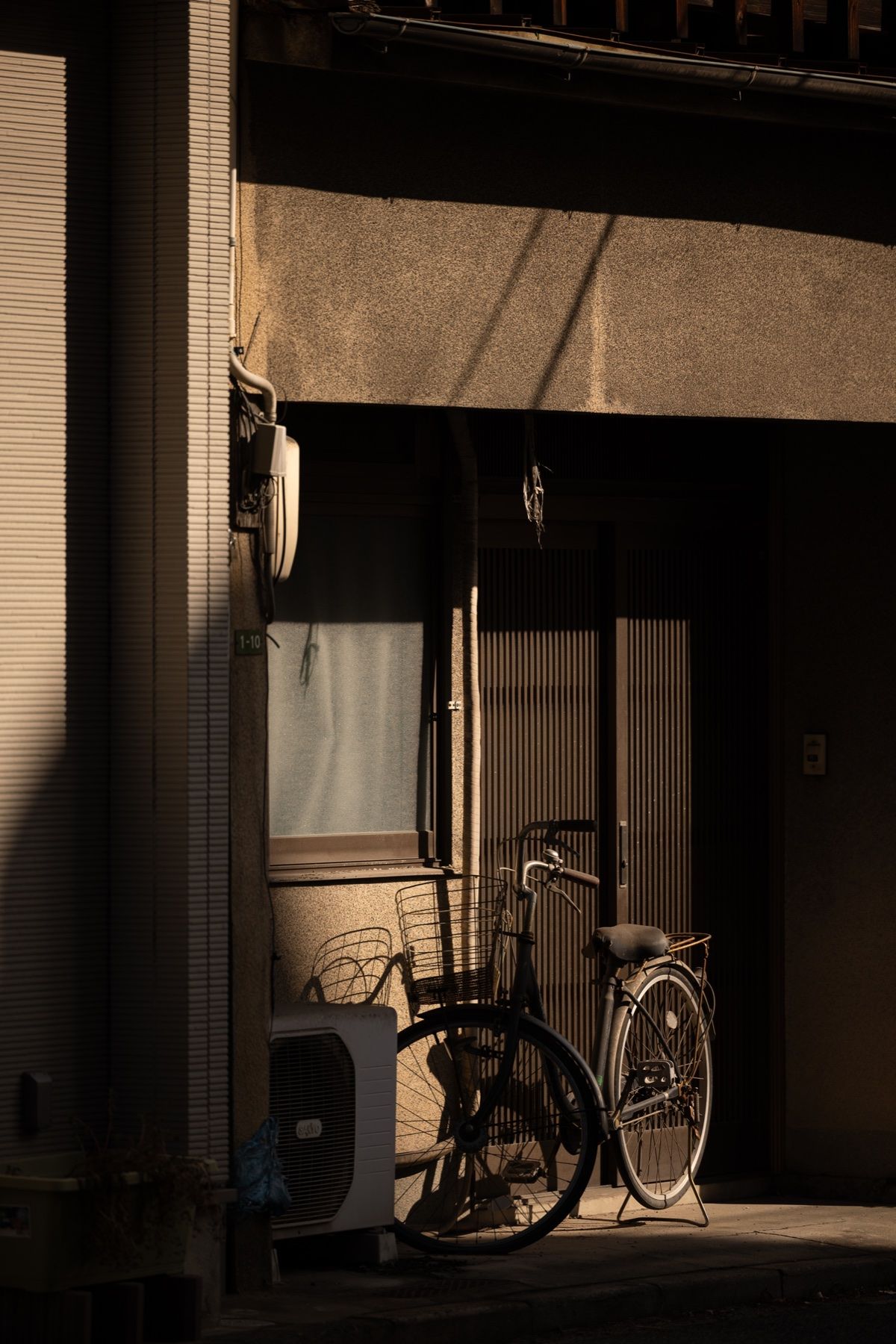 A bicycle in a quiet alley, warm light from a doorway