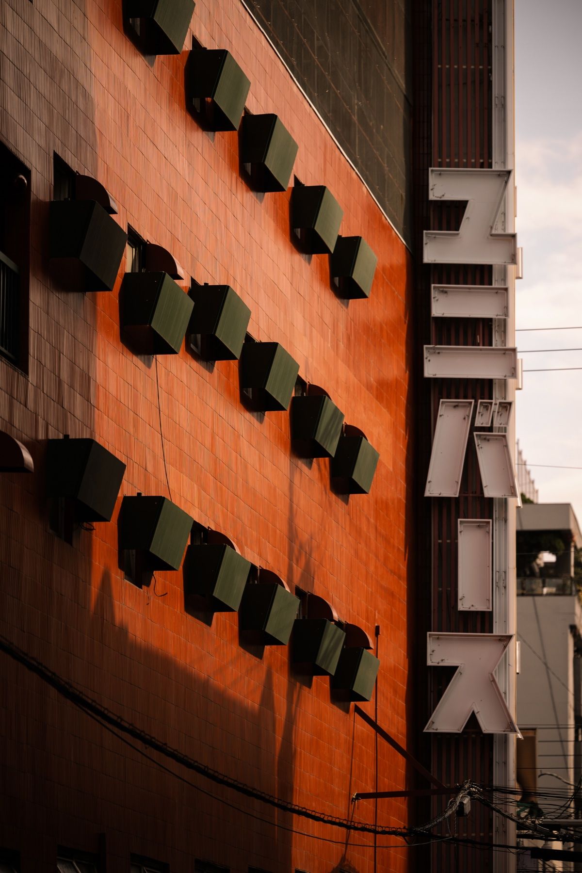 Lanterns and a vertical sign on a dark façade