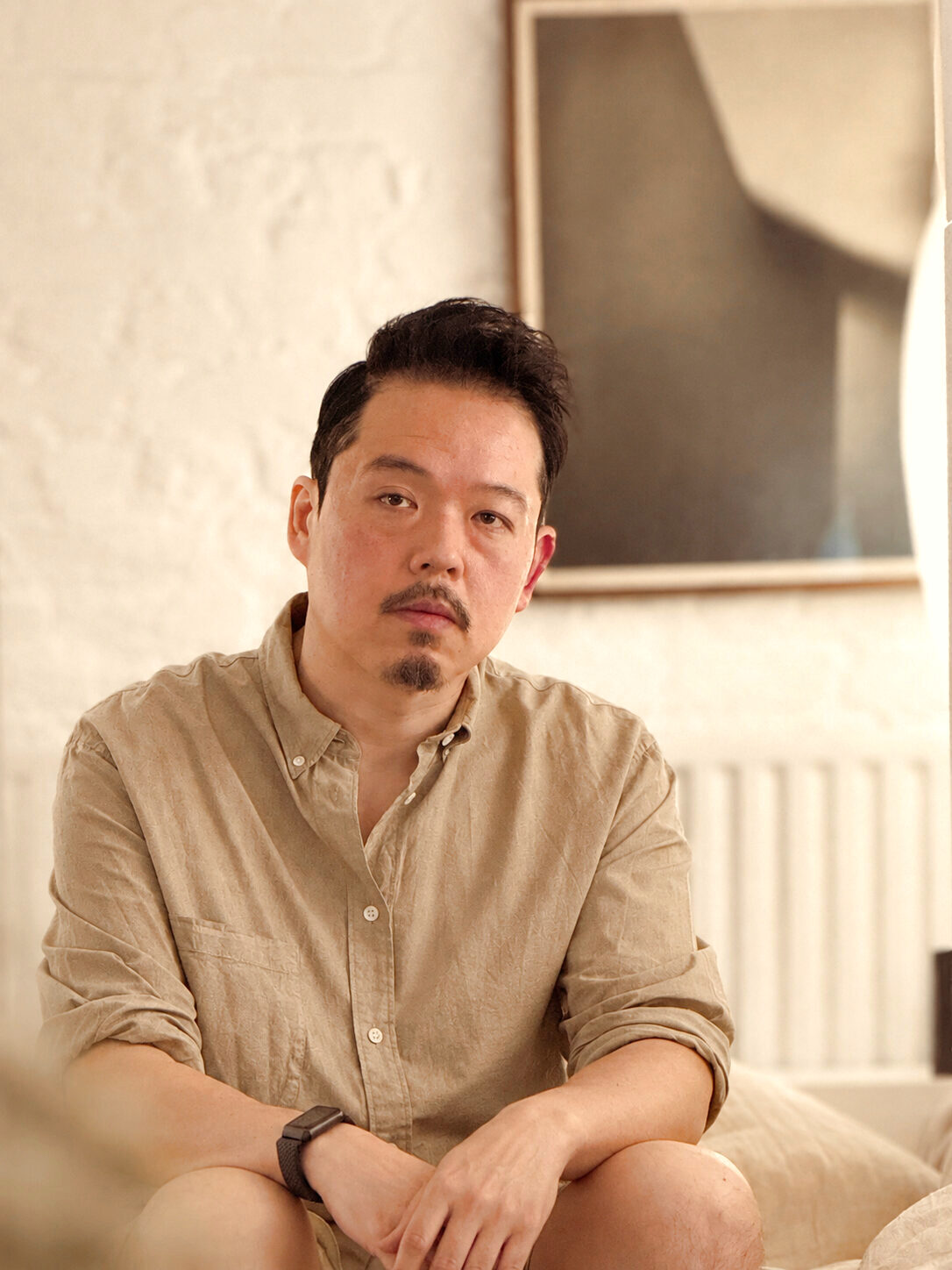 Alex Chan, design lead and photographer at Aura Studios, seated in a linen shirt