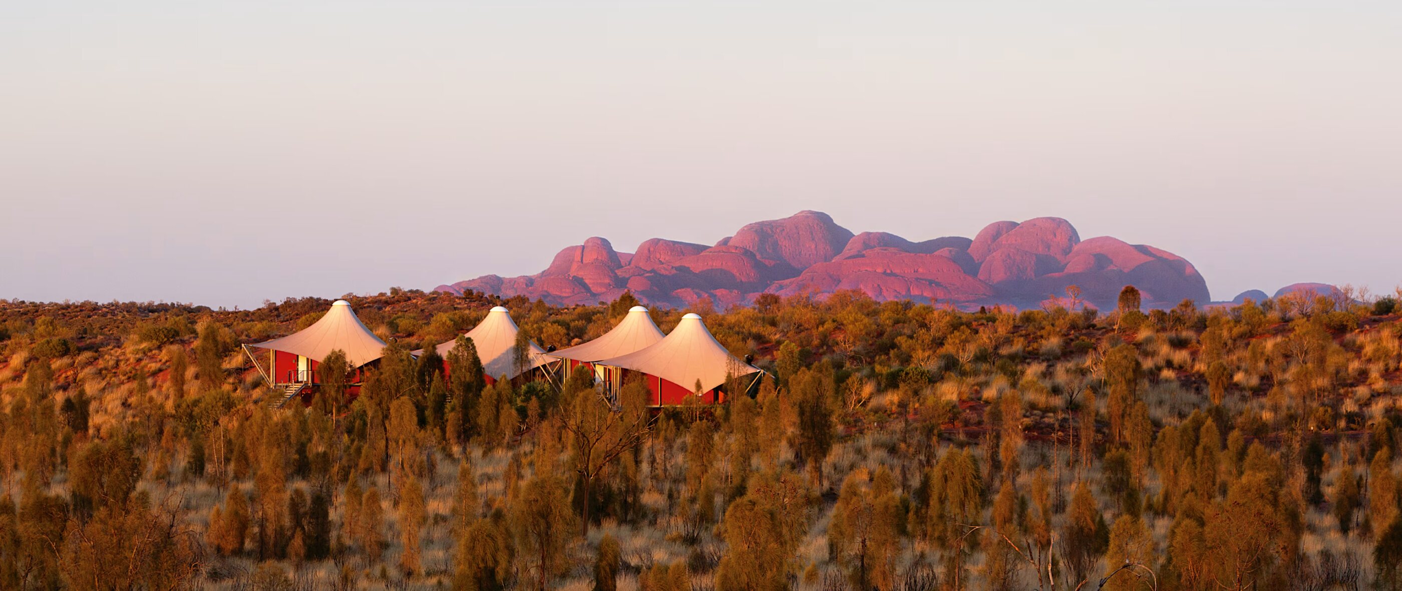 A tented camp facing red rock domes at dusk