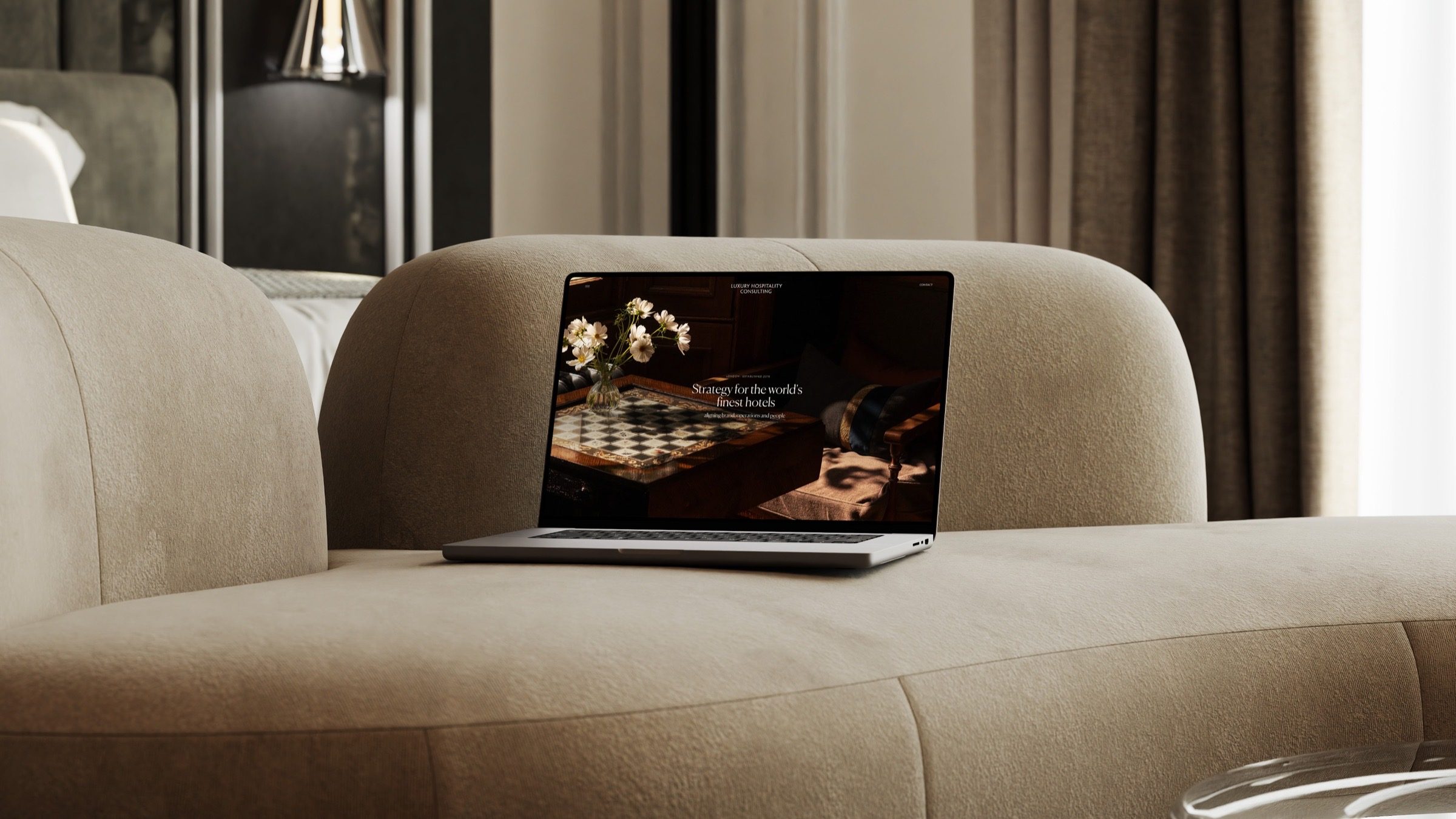 The Luxury Hospitality Consulting homepage on a laptop in a hotel suite
