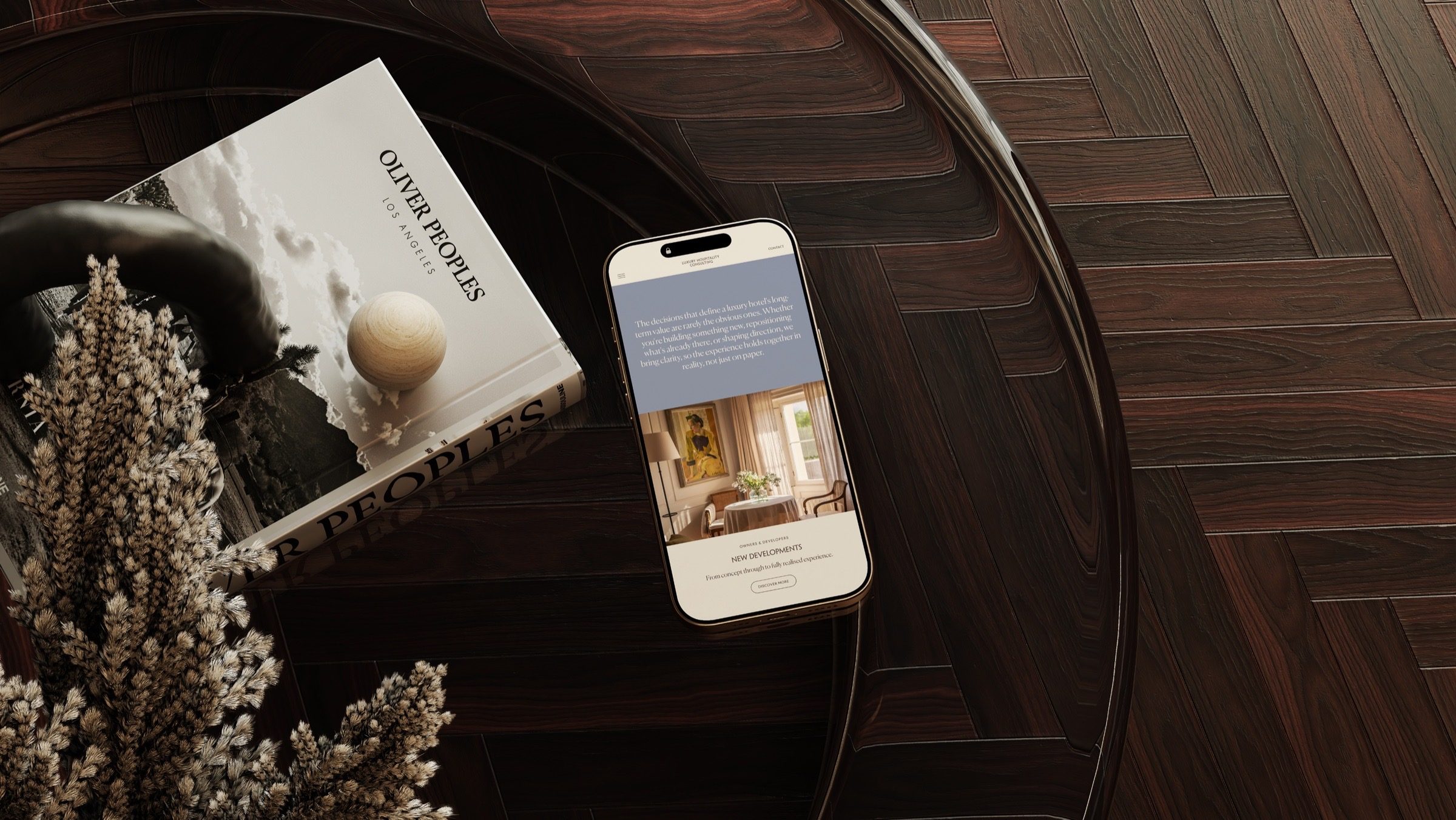 The Luxury Hospitality Consulting site on a phone, laid on a herringbone floor