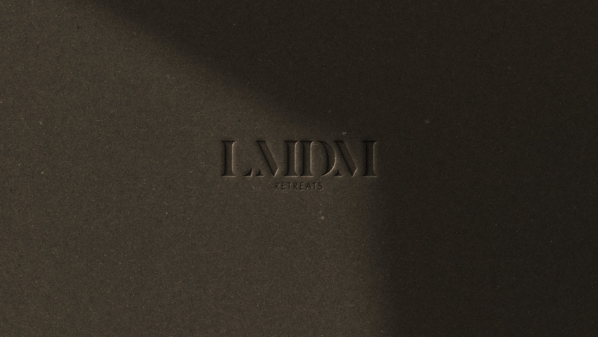 The LMDM Retreats wordmark pressed into dark paper