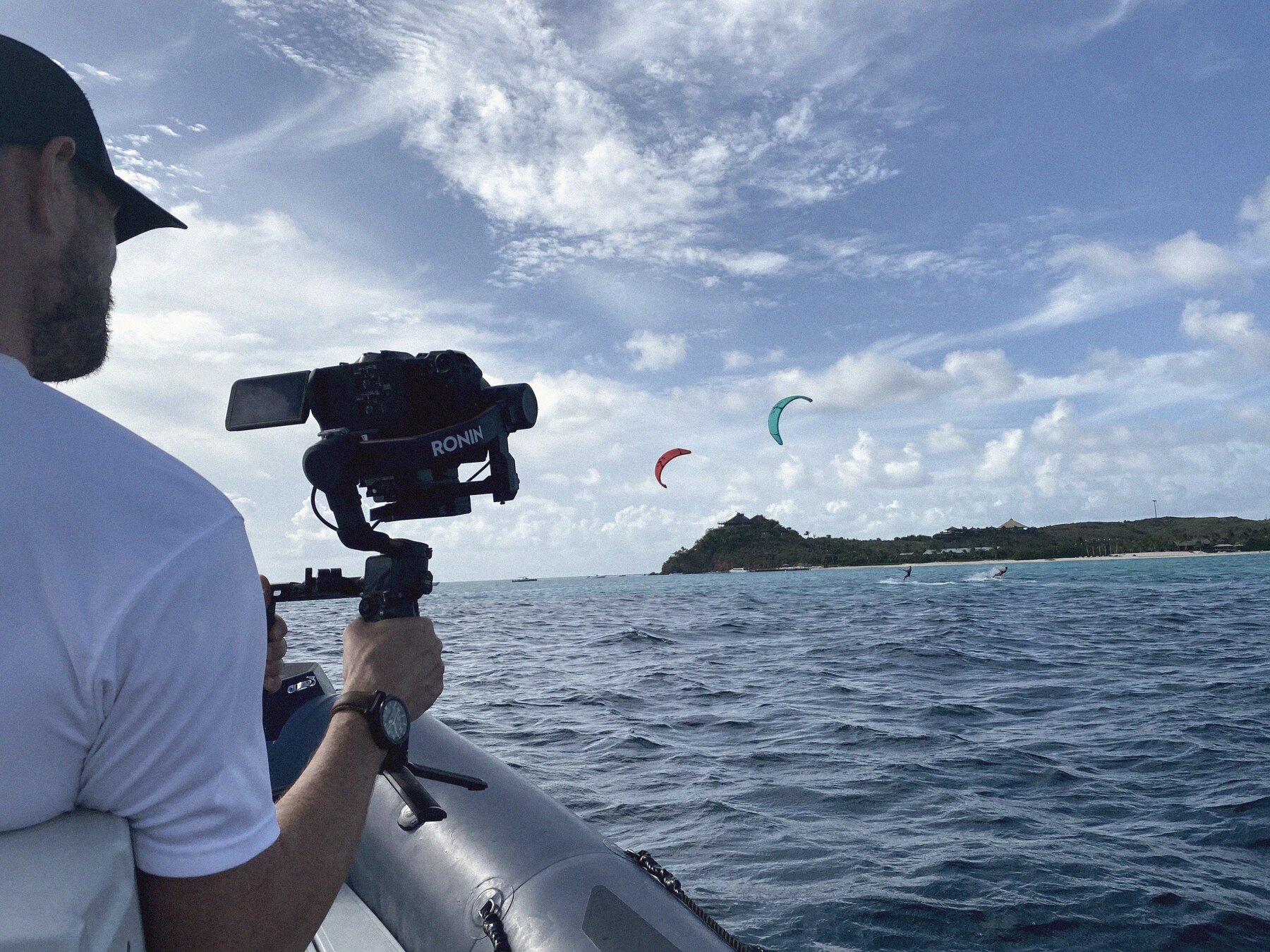 The camera operator filming from the boat, kitesurfers on the water
