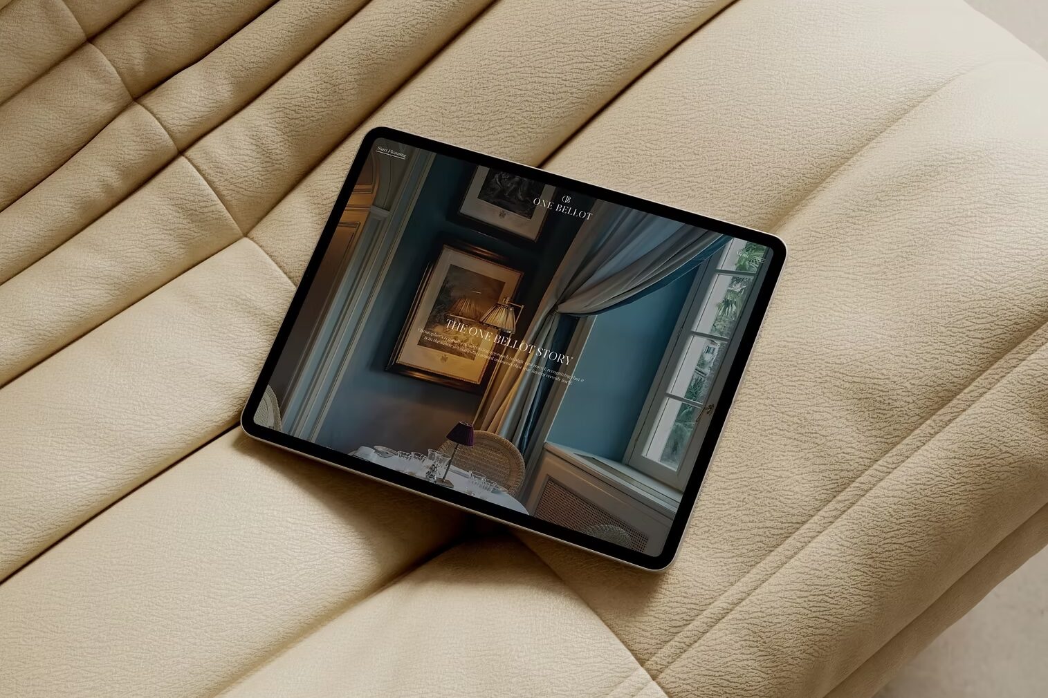 The One Bellot website on a tablet, resting on a cream sofa
