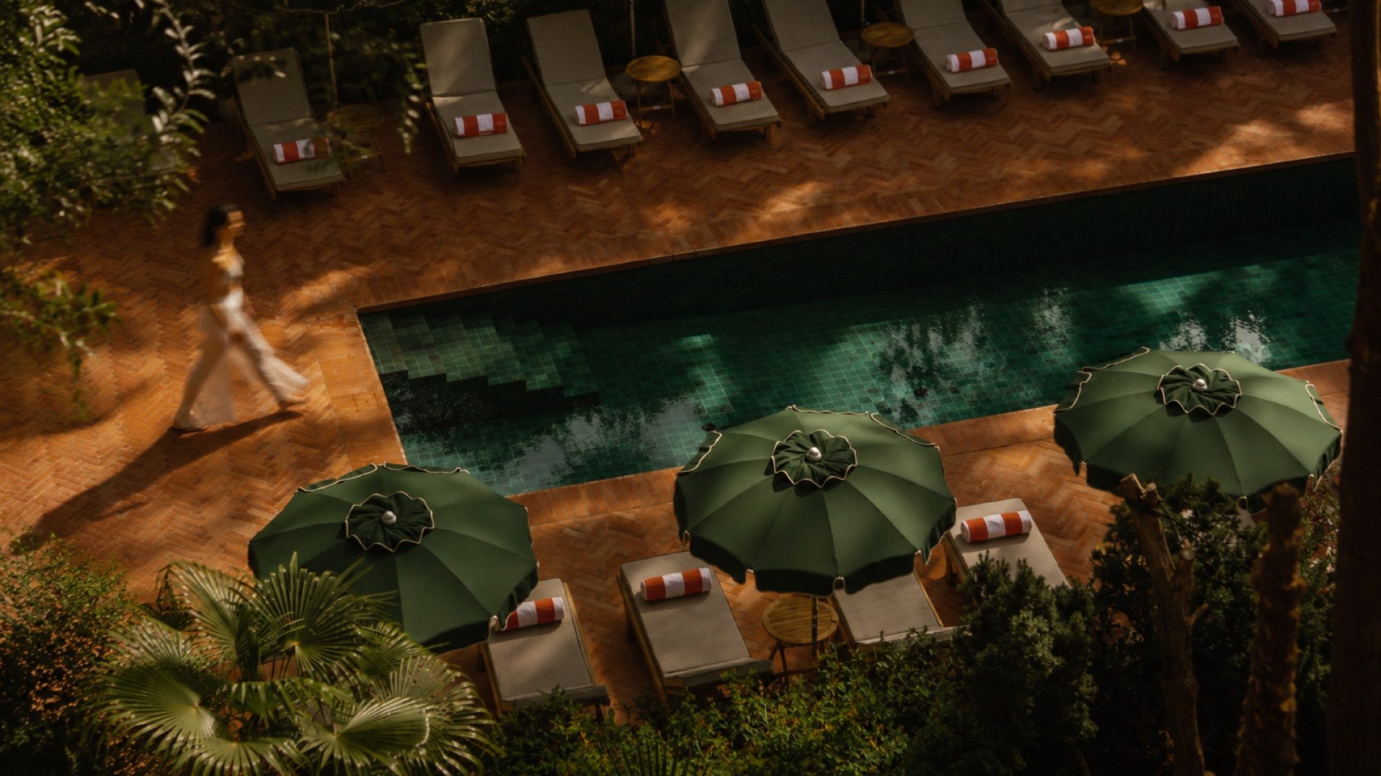 Green parasols around a pool, seen from above