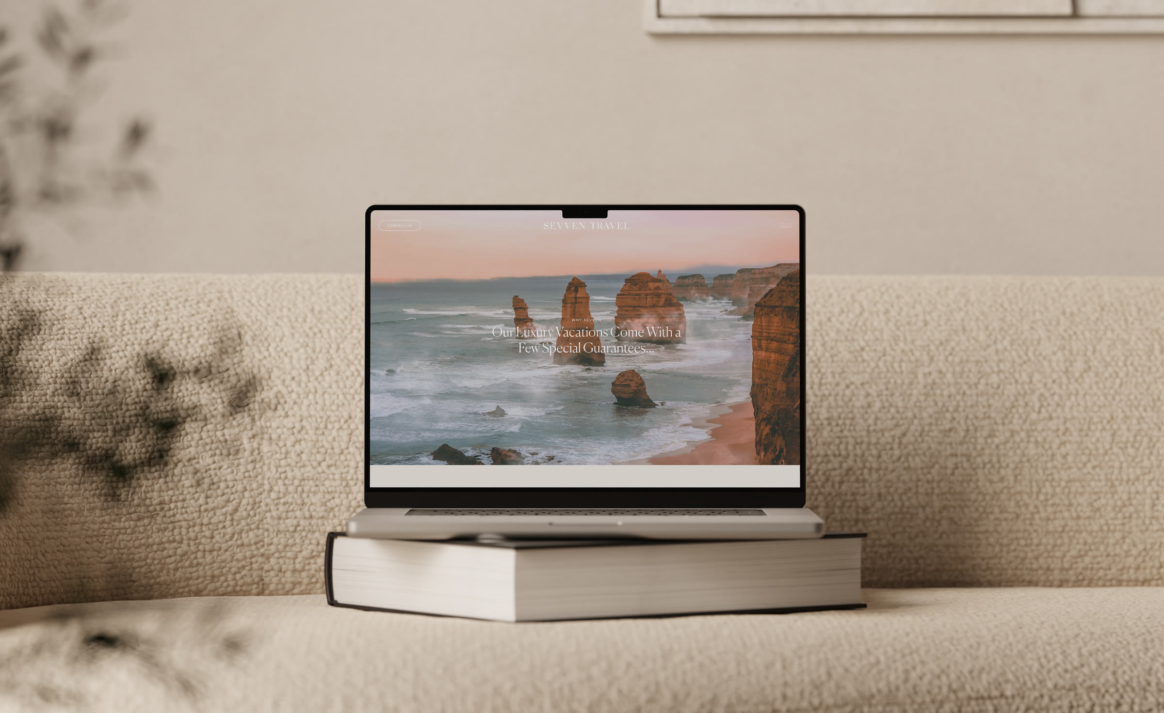 The Sevven Travel website on a laptop resting on a book