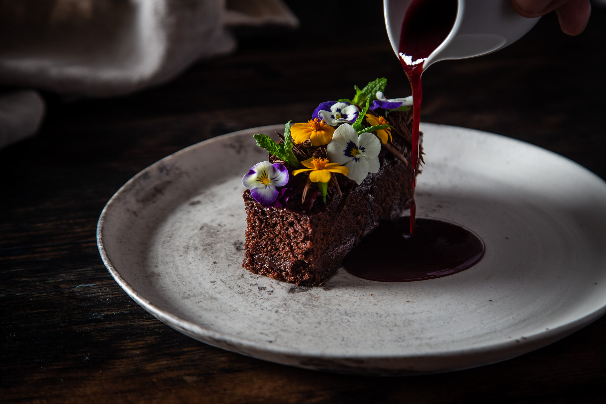 Sauce poured over a chocolate dessert dressed with flowers