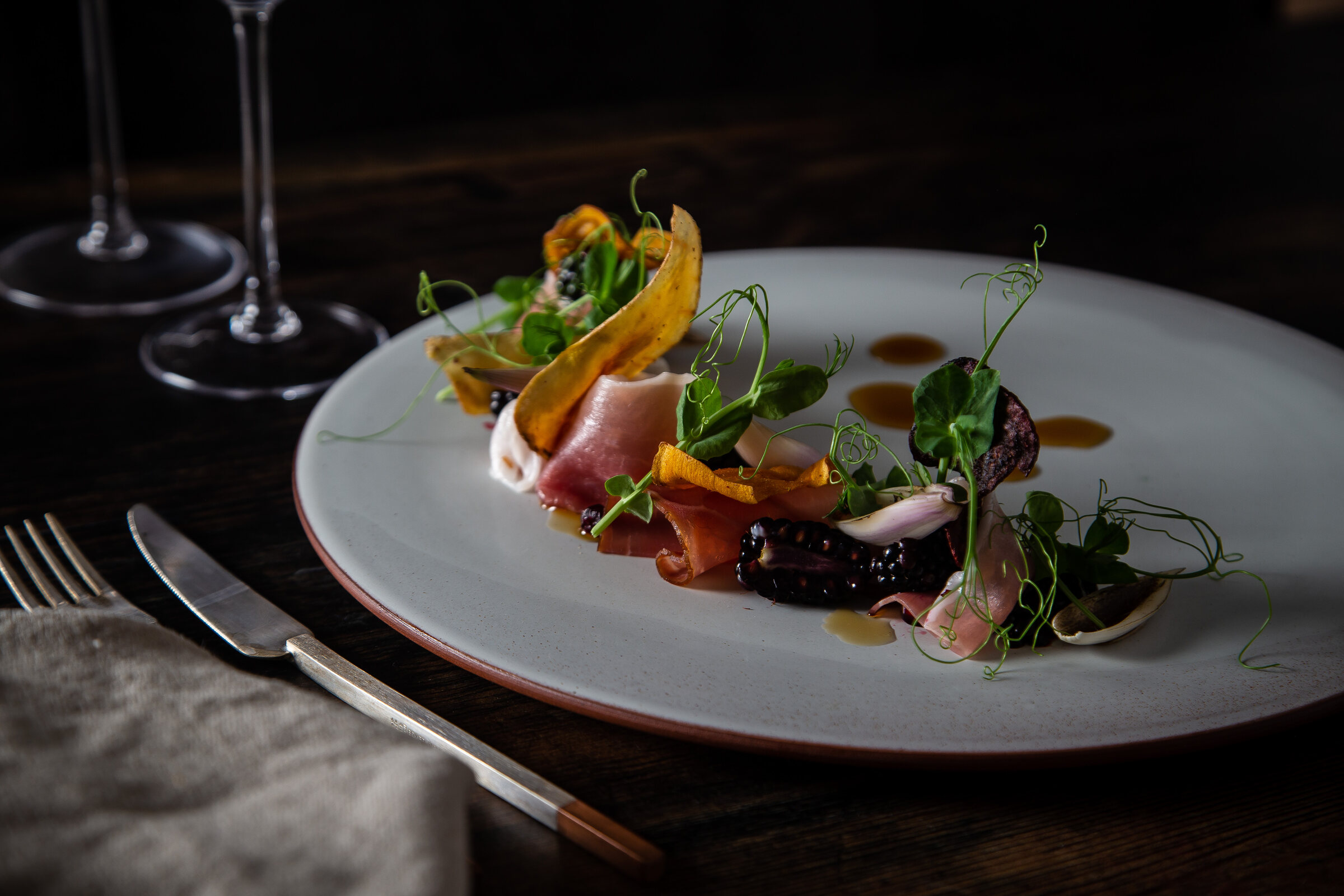 Cured ham, pickled vegetables and flowers on a white plate