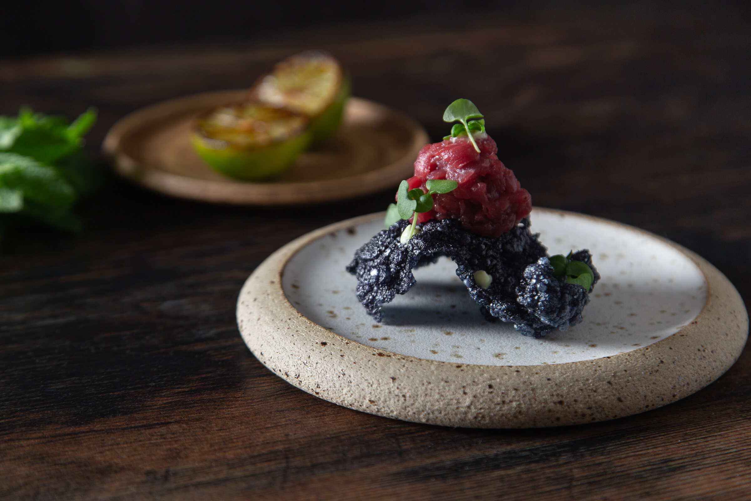Beef tartare on a squid-ink cracker, on a speckled stone plate