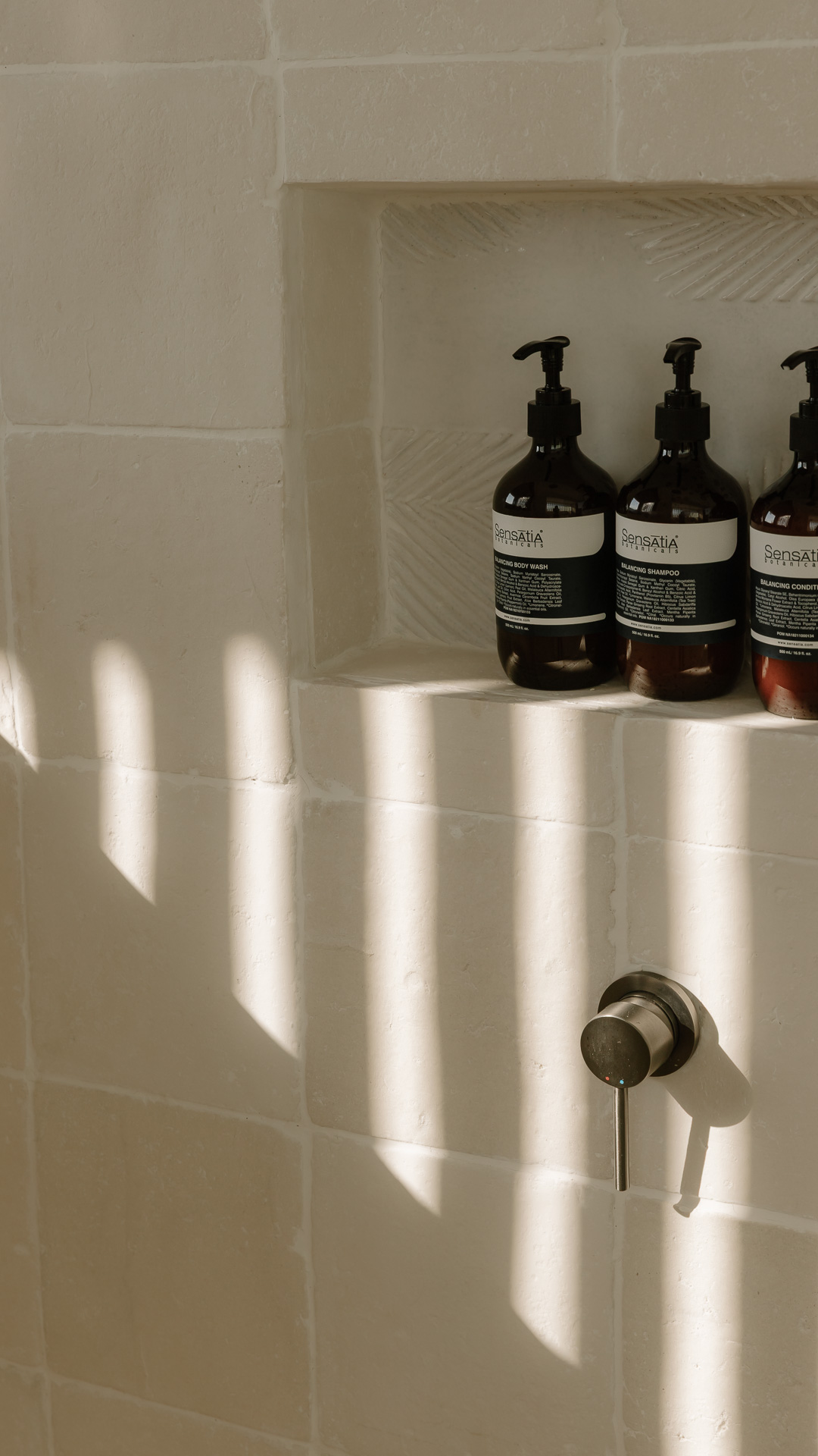 Bath amenities in a stone niche at Zambala, striped with afternoon light