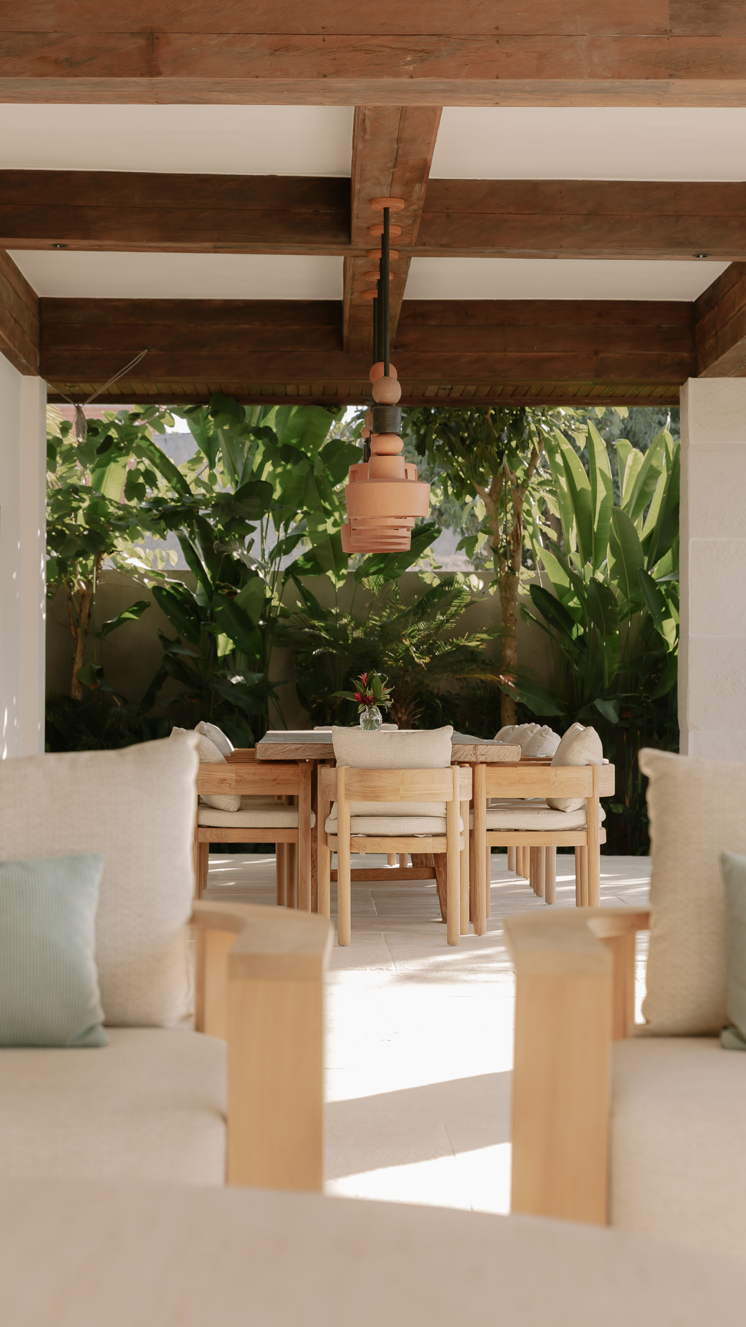 The open-air dining pergola at Zambala – timber beams, a terracotta pendant and the garden beyond